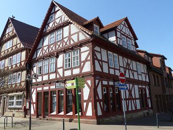 Fachwerkhaus mit rotem Gebälk in historischer Altstadt bei sonnigem Wetter.
